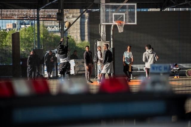 Parkgoers play basketball on Brooklyn Bridge Park Pier 2 under the watchful eye of NYPD.